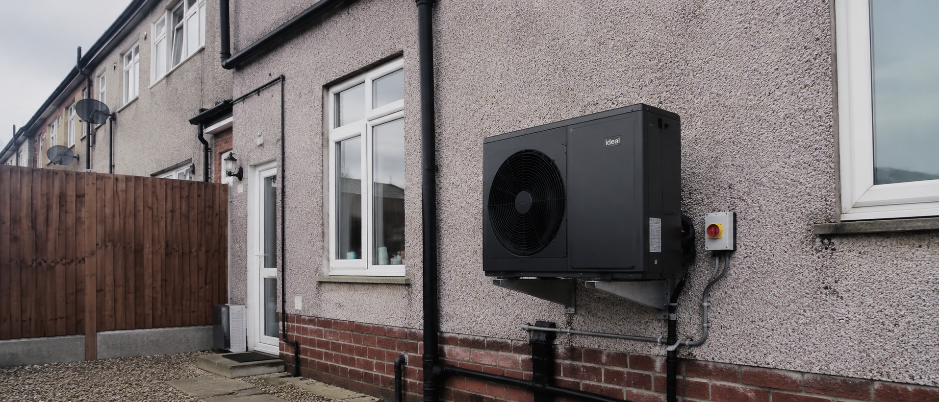 A heat pump unit on the exterior wall of an ordinary British house