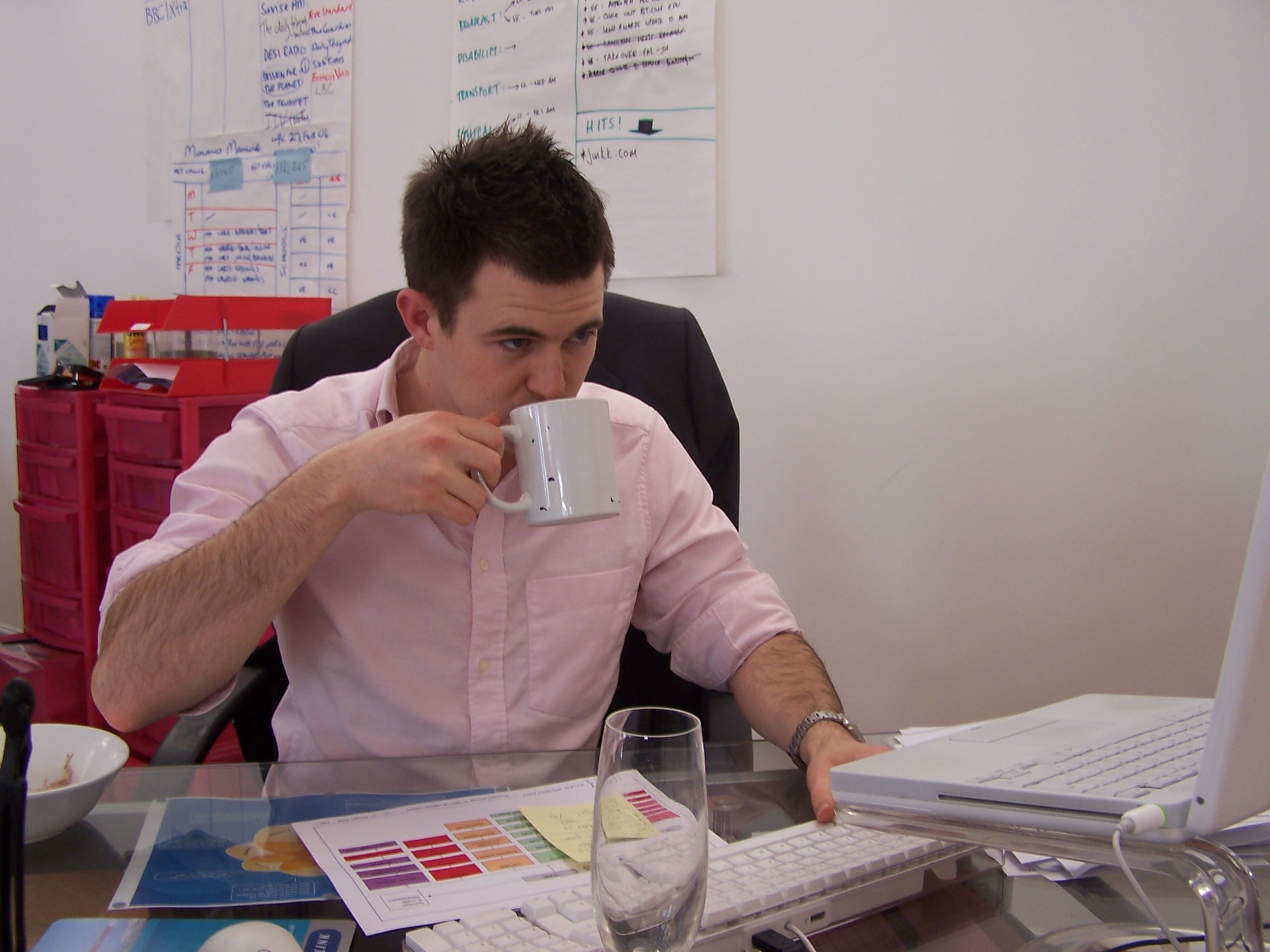 Christopher drinking tea at his desk in the PR agency